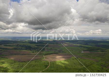 Aerial view of town or village with rows of buildings and curvy streets between green fields in summer. Countryside landscape from above. Aerial view of town or village with rows of buildings and curvy streets between green fields in summer. Countryside landscape from above. 132730425