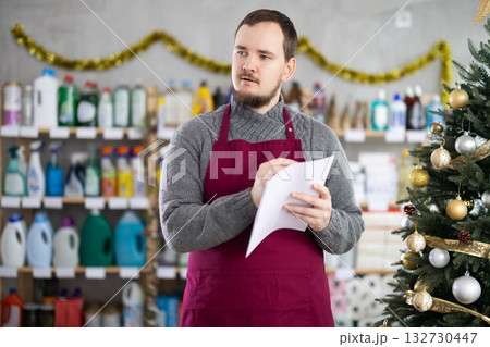 Man employee with paper, plans to replenish restock stores inventory on Christmas Eve Man employee with paper, plans to replenish restock stores inventory on Christmas Eve 132730447