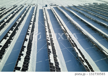 Aerial view of electrical power plant with solar panels covered with snow melting down in winter end for producing clean energy. Concept of low effectivity of renewable electricity in northern region Aerial view of electrical power plant with solar panels covered with snow melting down in winter end for producing clean energy. Concept of low effectivity of renewable electricity in northern region 132730565