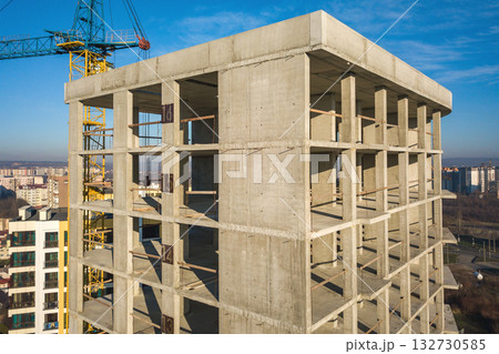 Aerial view of concrete frame of tall apartment building under construction in a city. Aerial view of concrete frame of tall apartment building under construction in a city. 132730585
