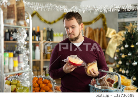 Customer choosing cheese for Christmas celebration in festive grocery store Customer choosing cheese for Christmas celebration in festive grocery store 132730589