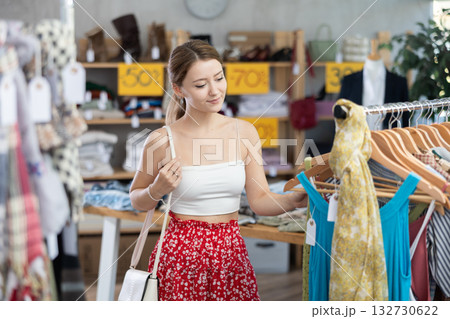 Young woman customer making choice and elect something summer clothing in store Young woman customer making choice and elect something summer clothing in store 132730622
