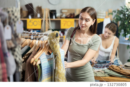 Woman chooses T-shirts against the background of a buyer Woman chooses T-shirts against the background of a buyer 132730805