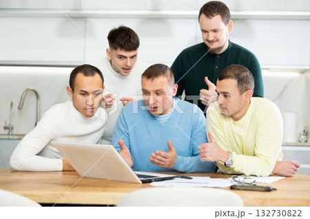 Group of men discussing with paperwork and laptop at home kitchen Group of men discussing with paperwork and laptop at home kitchen 132730822