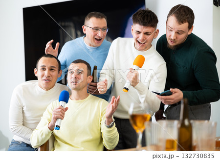 Happy male friends having fun while singing karaoke at a bar. Having fun, celebrating. holiday, leisure, party concept Happy male friends having fun while singing karaoke at a bar. Having fun, celebrating. holiday, leisure, party concept 132730835