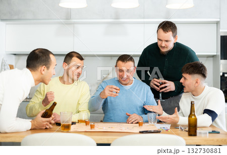 Man drinking shot while losing board game with friends Man drinking shot while losing board game with friends 132730881