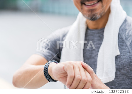 ジョギング中にスマートウォッチをチェックする男性。 132732558