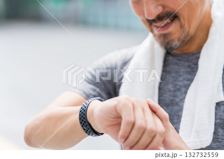 ジョギング中にスマートウォッチをチェックする男性。 132732559