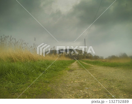 A Serene Pathway Leading Up to a Historic Hilltop Under Beautiful, Soft Clouds Above 132732889