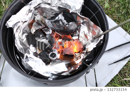 BBQの着火剤に空気を送り込んで火をつける 132733154