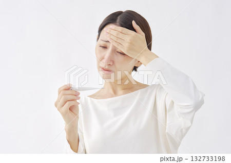 体温計で体温を測る女性 白背景 体温計で体温を測る女性 白背景 132733198