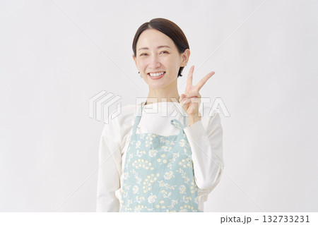 エプロンをつけた女性　ピースサイン　白背景 132733231