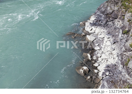 Rugged rocky cliff meets Katun river along a quiet, natural coastline 132734764