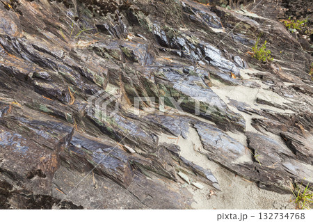 Layered slate rocks meet light sand in a rugged coastal scene. Altai, Russia 132734768