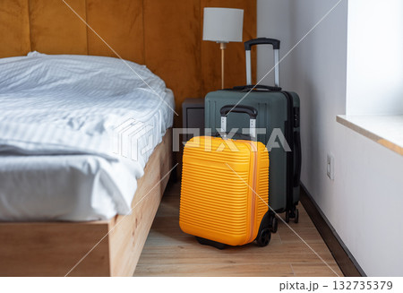 Luggage standing beside bed in modern hotel room 132735379