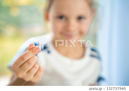 Girl showing finger heart gesture in a portrait with hand in sharp focus and face blurred in the background. Youth expressing love and modern pop culture trend from Gen Z to younger kids. 132737940