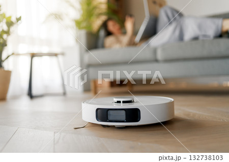 White robotic vacuum cleaner on wooden floor 132738103