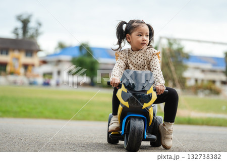 toddler girl riding an electric motorcycle toy in park toddler girl riding an electric motorcycle toy in park 132738382