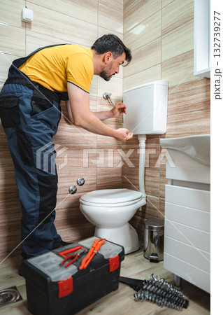 Plumber repairing toilet cistern in a bathroom 132739277