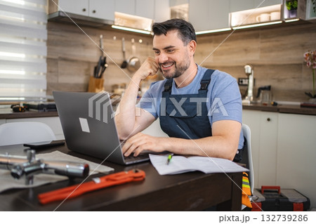 Plumber working on laptop, searching for new work offers online Plumber working on laptop, searching for new work offers online 132739286