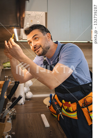 Electrician installing led strip lights under kitchen cabinets 132739287