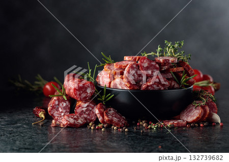 Sliced dry cured sausages with spices on a black table. Sliced dry cured sausages with spices on a black table. 132739682