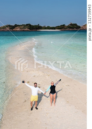 A couple enjoys a sunny day on a sandy beach near Redang Island in Malaysia, surrounded by clear blue waters A couple enjoys a sunny day on a sandy beach near Redang Island in Malaysia, surrounded by clear blue waters 132739943