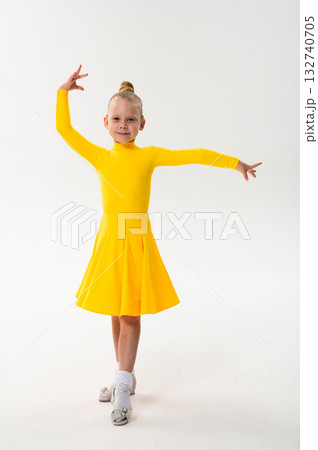 Smiling child in bright yellow practicing choreography with hearing device. Confidence, concentration, and harmony of movement despite deafness, showing inclusion and technological progress in Smiling child in bright yellow practicing choreography with hearing device. Confidence, concentration, and harmony of movement despite deafness, showing inclusion and technological progress in 132740705