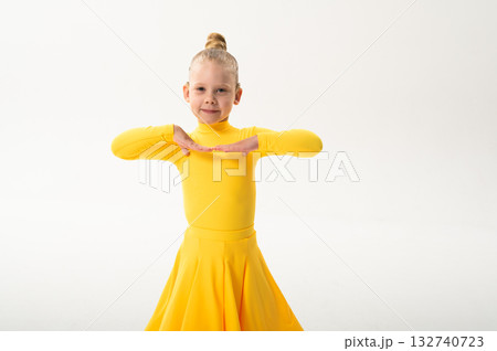Smiling child in bright yellow practicing choreography with hearing device. Confidence, concentration, and harmony of movement despite deafness, showing inclusion and technological progress in Smiling child in bright yellow practicing choreography with hearing device. Confidence, concentration, and harmony of movement despite deafness, showing inclusion and technological progress in 132740723