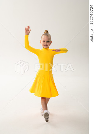 Little girl in yellow dress dancing with cochlear implant. Overcoming hearing loss through rhythm, art, inclusion, and strength of spirit in artistic gymnastics and ballroom dance. Little girl in yellow dress dancing with cochlear implant. Overcoming hearing loss through rhythm, art, inclusion, and strength of spirit in artistic gymnastics and ballroom dance. 132740724
