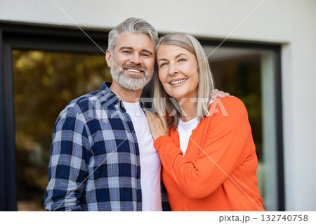 Two people standing at the house entrance and looking contented 132740758