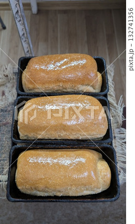 Delicious, Freshly Baked Bread Loaves Placed in Pans, Ready for Enjoyment and Tasting 132741356