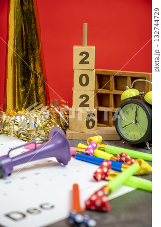 Stack of wooden cubes with the number 2026 with an alarm clock, plastic horn, and party blowers. Happy New Year concept or Celebration 132744729