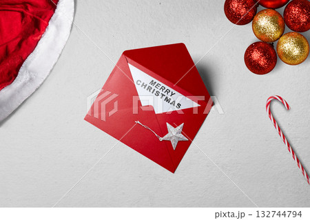 Greeting of Merry Christmas text in a red envelope with a candy cane and a Christmas ornament. Mockup or Copy space. Holiday greetings or winter themes. Concept of the Merry Christmas celebration 132744794