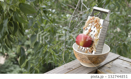 Grate the apple on a metal grater. Grate the apple on a metal grater. 132744851