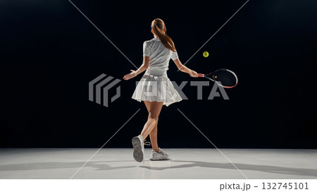 Female tennis player follow-through shot on studio background. 132745101