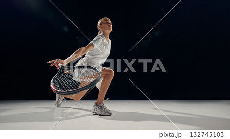 Female tennis player crouching defense low shot on dark background minimal light 132745103