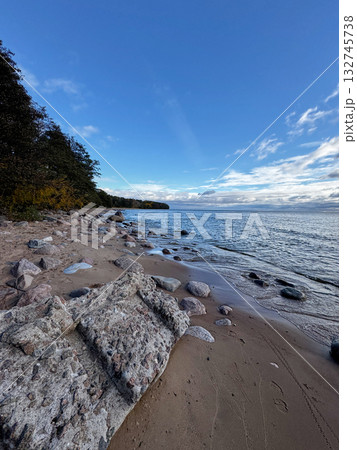 Sandy beach with large rock formations and calm sea under blue sky. Sandy beach with large rock formations and calm sea under blue sky. 132745738