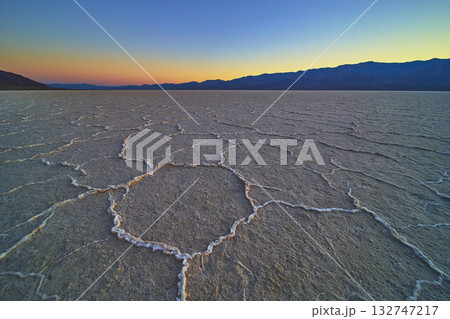 Badwater Basin Salt Flats at Golden Hour with Mountain Silhouette and Cracked Desert Floor Badwater Basin Salt Flats at Golden Hour with Mountain Silhouette and Cracked Desert Floor 132747217