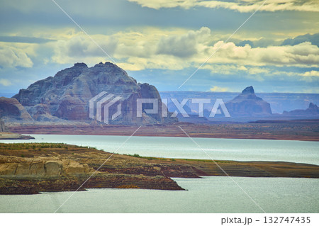 Lake Powell Sandstone Cliffs and Calm Water with Dramatic Cloudy Sky Lake Powell Sandstone Cliffs and Calm Water with Dramatic Cloudy Sky 132747435
