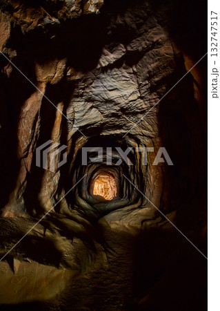 Rugged Rock Tunnel Interior with Warm Light and Graffiti Belly of the Dragon Cave 132747517