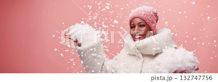 African American woman in winter coat joyfully playing with snowflakes, copy space for design 132747756