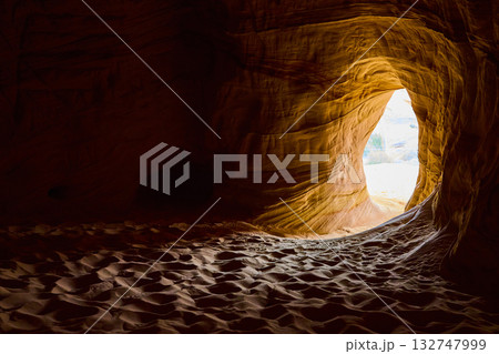 Sandstone Cave Interior with Sunlit Entrance and Rippling Sand Floor 132747999