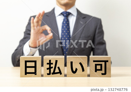 「日払い可」と書かれたブロックとOKポーズをするビジネスマン 132748776