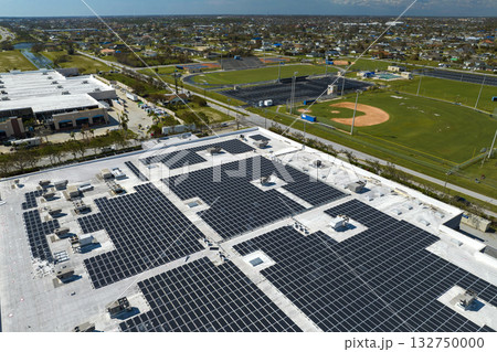 Aerial view of blue photovoltaic solar panels mounted on industrial building roof for producing green ecological electricity. Production of sustainable energy concept 132750000