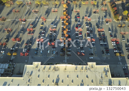 Aerial view grocery shopping mall and many colorful cars parked on parking lot with lines and markings for parking places and directions. Place for vehicles in front of a strip mall plaza Aerial view grocery shopping mall and many colorful cars parked on parking lot with lines and markings for parking places and directions. Place for vehicles in front of a strip mall plaza 132750043