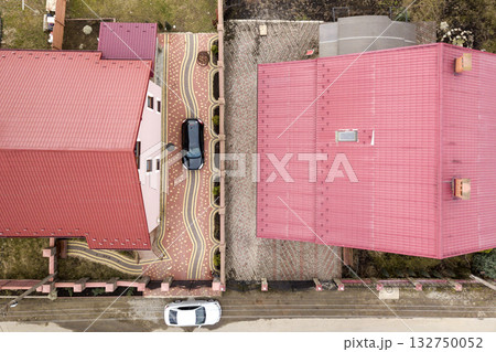 Aerial top view of house with shingle roof and brick chimney in quiet neighborhood, black car on paved yard. Well maintained property concept. Aerial top view of house with shingle roof and brick chimney in quiet neighborhood, black car on paved yard. Well maintained property concept. 132750052