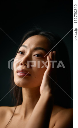 Woman touching temple with calm expression and balanced natural beauty. 132750240