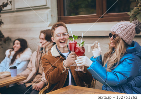 Friends toasting with winter cocktails outdoors in cozy city cafe 132751262