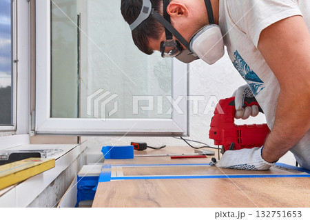repairman using electric jigsaw and cutting hole for the sink in the kitchen countertops 132751653